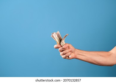 Take My Money, The Willingness To Pay For A Cool Product, A Concept. A Man's Hand Clutches A Wad Of Cash, A Photo On A Blue Background