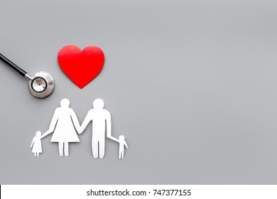 Take out health insurance for family. Stethoscope, paper heart and silhouette of family on grey background top view copyspace