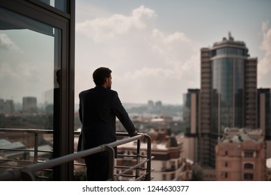 Take a pause. Full length back side portrait of businessman thoughtful standing on office balcony. Copy space on right