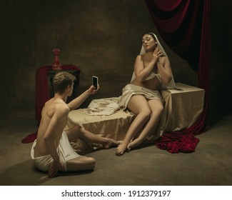 Take photo for social. Modern remake of classical artwork with modern tech theme - young medieval couple on dark background, golden colored. Concept of technologies, devices, communication, ad.
