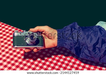 Take a picture. Concept of pop art photography. Using retro gadgets. Human hand holding photo camera isolated on green background. Vintage, retro 80s, 70s. Complementary colors. Concept of memory