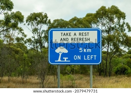 Take a rest and refresh roadside sign for rest area 5 kilometers ahead on left