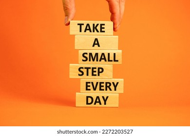 Take a small step every day symbol. Wooden blocks with words Take a small step every day. Beautiful orange background, copy space. Businessman hand. Business, step every day concept.