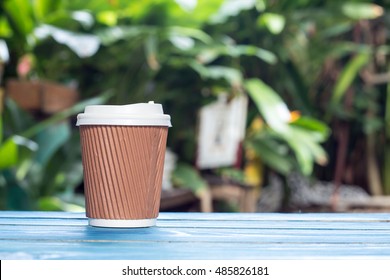 Takeaway Coffee Cup  On The Blue Table With Garden Background