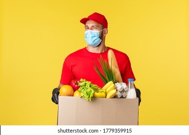 Takeaway Delivery, Food, Covid-19 Quarantine And Groceries Concept. Friendly Handsome Courier Bring Grocery Order To Client Office Or Home, Wear Medical Mask And Gloves, Hold Box With Foodstuff