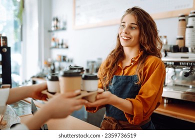 Takeaway food concept. A beautiful female barista gives to-go coffee to a client. Owner of a small business, a coffee shop,  behind the bar. Business concept. - Powered by Shutterstock