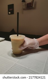 Taken At Uthman Ibn Affan,Al Muraikabat, Dammam,Saudi Arabia,on 9th Of July 2022: Evening Dark Background With A Close Up Photo Of A Waiter's Hands Holding A Cup Of Iced Spanish Latte On The Counter.