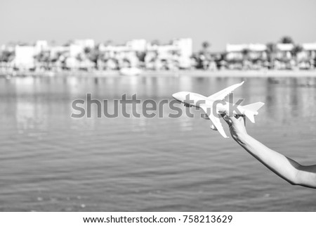 takeoff of white toy plane in female hand on sunny blurred natural background with water. business traveling and vacation. freedom and inspiration. airmail and postal delivery concept, copy space
