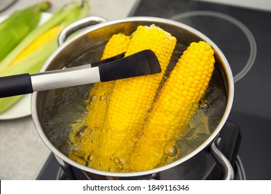 Taking boiled corn from pot with tongs in kitchen, closeup - Powered by Shutterstock