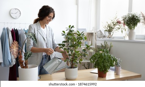 Taking Care Of Green Friends. Positive Millennial Woman Employee Office Manager Starting Workday With Watering Flowers. Small Business Owner Water Indoor House Plants In Studio Workroom Shop Using Can