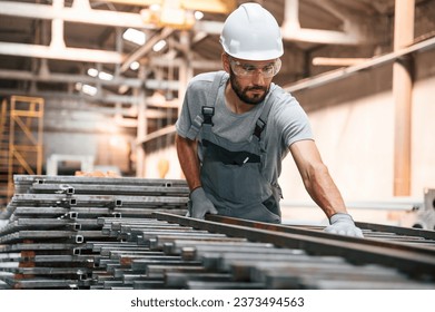 Taking care of metal products. Young factory worker in grey uniform. - Powered by Shutterstock