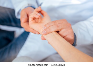 Taking Care Of Your Health. Close Up Of Medical Worker Putting His Fingers On A Wrist Of A Female Patient While Checking Her Pulse During An Appointment.