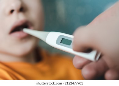 Taking The Child's Temperature. Oral Thermometer For A Child. High Temperature In A Child