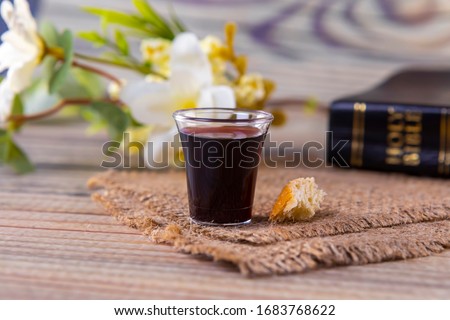 Taking communion concept - the wine and the bread symbols of Jesus Christ blood and body with Holy Bible. Easter Passover and Lord Supper concept Focus on glass.