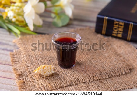Taking communion concept - the wine and the bread symbols of Jesus Christ blood and body with Holy Bible. Easter Passover and Lord Supper concept Focus on glass.
