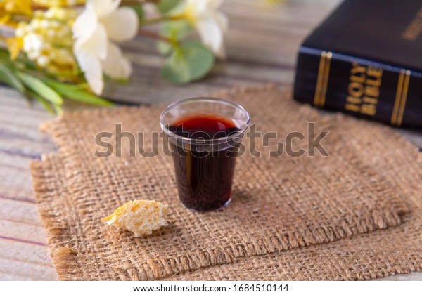 Taking communion concept - the\
wine and the bread symbols of Jesus Christ blood and body with Holy\
Bible. Easter Passover and Lord Supper concept Focus on\
glass.