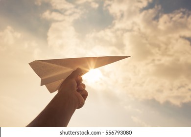 Taking flight! Hand holding paper airplane in the sky. 
