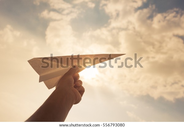 Taking\
flight! Hand holding paper airplane in the sky.\
