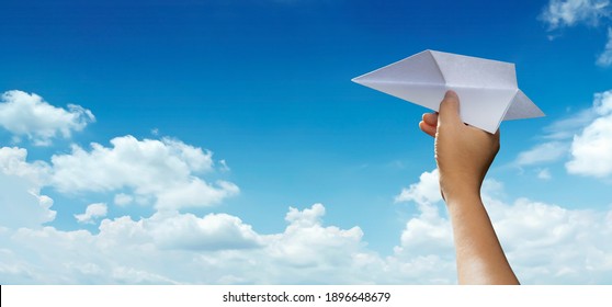 Taking flight. Man's hand holding paper plane in sky show concept of journey, travel, dream, freedom, start up, new business. Hand is throwing paper airplane against blue sky with empty space for text