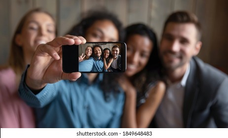 Taking Group Selfie. Blurred Portrait Of Four Diverse Multiethnic Millennial Friends Students Coworkers Hugging Smiling And Looking At Camera Showing Spectator Self Picture Making On Smartphone Webcam