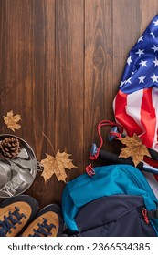 Taking a hike to revel in the colors of autumn. Top view vertical shot of USA flag, metal utensils, boots, rucksack, trekking sticks, cones, dry leaves on wooden background with promo zone - Shutterstock ID 2366534385