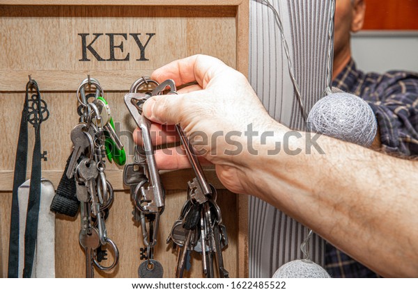 Taking the keys from the hanger. The concept of\
leaving home, retrieving the keys to the locks. The man takes the\
keys from the hanger.