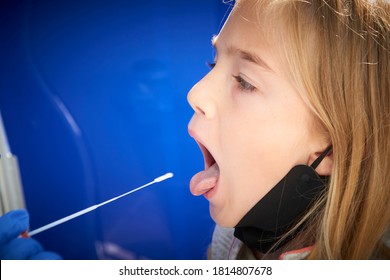 Taking A Medical Sample - A Throat Swab For A Coronavirus Test. Nurse Takes A Sample From Child Blond Girl For Covid 19 Test. An Unpleasant Experience For Children