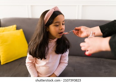 Taking A Medicine. Adult Mom Giving Cough Syrup To A Sick Little Child At Home