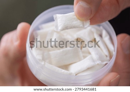 taking nicotine pouch background plastic box surface close up of hands holding white snus portion swedish tobacco free alternative smokeless product concept of addiction, bad habits, nicotine delivery
