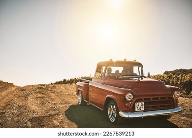Taking the old truck for a cruise. Shot of a cheerful young family driving in a red pickup truck on a rural road outside.