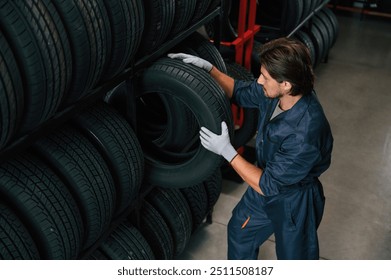 Taking one tire to for changing. Man is in the tire fitting car service.