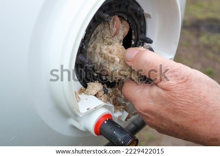 Taking out an electric heater from boiler or water heater to remove lime scale residue on it as part of a maintenance.