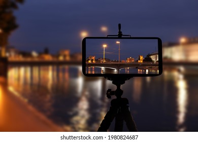 Taking photo of beautiful cityscape at night with smartphone mounted on tripod