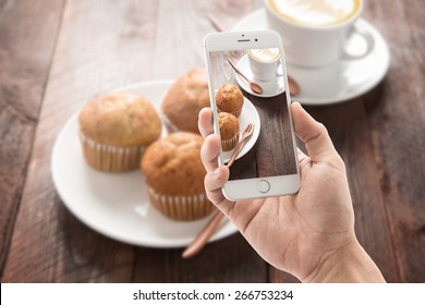 Taking photo of muffin and coffee on wooden table. - Powered by Shutterstock