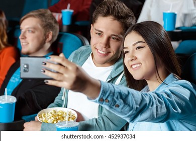 Taking a pic. Shot of a beautiful multicultural young loving couple taking a selfie at the cinema - Powered by Shutterstock