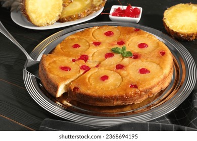 Taking piece of delicious cut pineapple pie with cherry and mint on dark wooden table - Shutterstock ID 2368694195