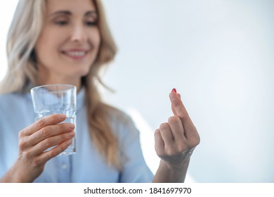 Taking Pills. Blonde Female Holding Glass Of Water, Taking Red Pill