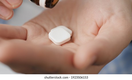 Taking Pills. Two Big White Square Pills Fall Into Palm Of Hand From Pill Bottle. Close-up, Front View, Center Composition