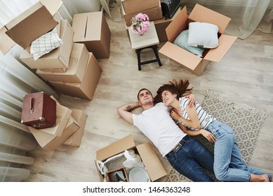 Taking a rest. Lying down on the floor. Cheerful young couple in their new apartment. Conception of moving.
