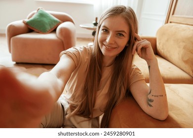 Taking a selfie. Beautiful young woman is sitting at home. - Powered by Shutterstock