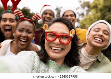 Taking selfie, wearing festive hats, multiracial friends celebrating christmas outdoors. celebration, holiday, winter, happiness, gathering - Powered by Shutterstock