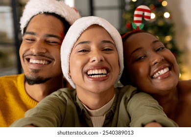 Taking selfie, young multiracial friends wearing santa hats smiling at christmas, at home. holidays, party, festive, winter, tradition - Powered by Shutterstock