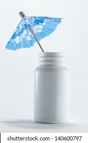 Taking A Sick Leave / Paid Sick Days / Sick Pay  A Blue Paper Cocktail Umbrella On A White Pill Box / Pill Cane