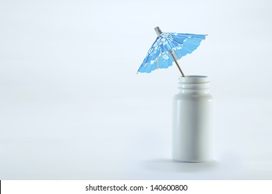 Taking A Sick Leave / Paid Sick Days / Sick Pay  A Blue Paper Cocktail Umbrella On A White Pill Box / Pill Cane