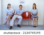 Taking up space. Two job candidates looking disgustedly at a young man sprawled on the chairs next to them.