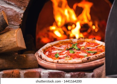 Taking tasty pizza out of oven in restaurant kitchen