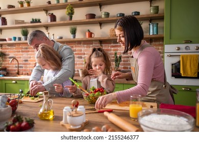 Taking video from the up of a large rustic kitchen young family dad mom and two girls preparing a healthy lunch form the legumes at the kitchen island