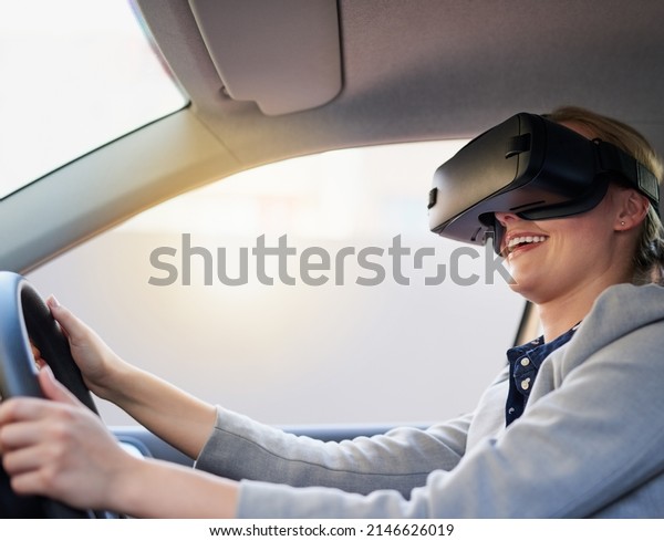 Taking\
virtual reality on the road. Cropped shot of a young businesswoman\
driving while wearing a virtual reality\
headset.