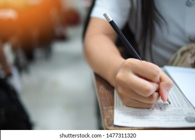 Taking Written Test Or Writing Assignment In Classroom. Education Or Academic Picture Of Student Or Learner Holding A Pencil And Working On Quiz Or Writing Test At The Evaluation Center Of College