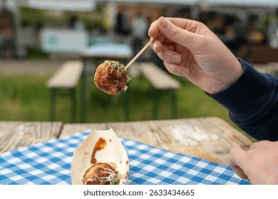 Takoyaki - traditional Japanese street food in hand, Osaka outdoor snack with octopus Takoyaki fried balls, delicious squid dumplings